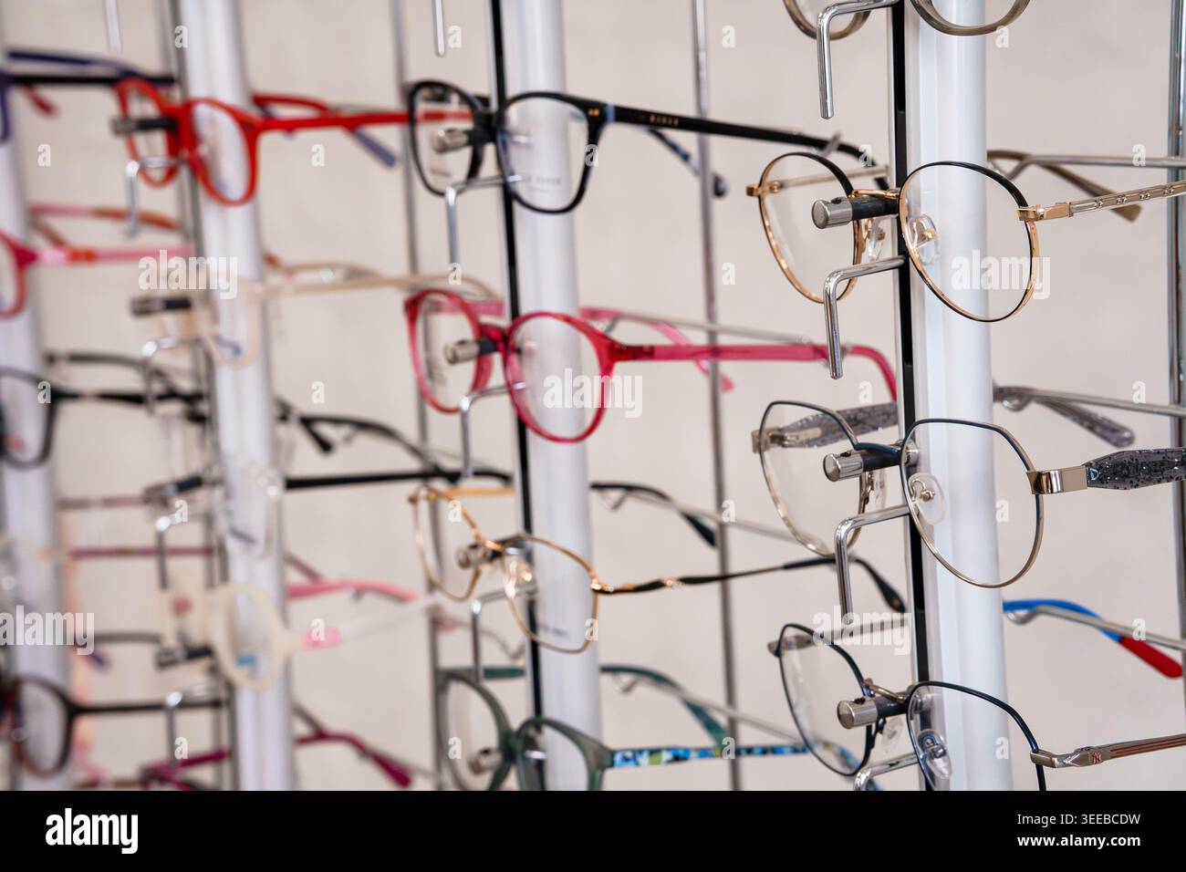 Montature per occhiali assortite ed eleganti su scaffale del negozio che mostrano le tendenze della moda e soluzioni ottiche per i clienti che cercano occhiali Foto Stock