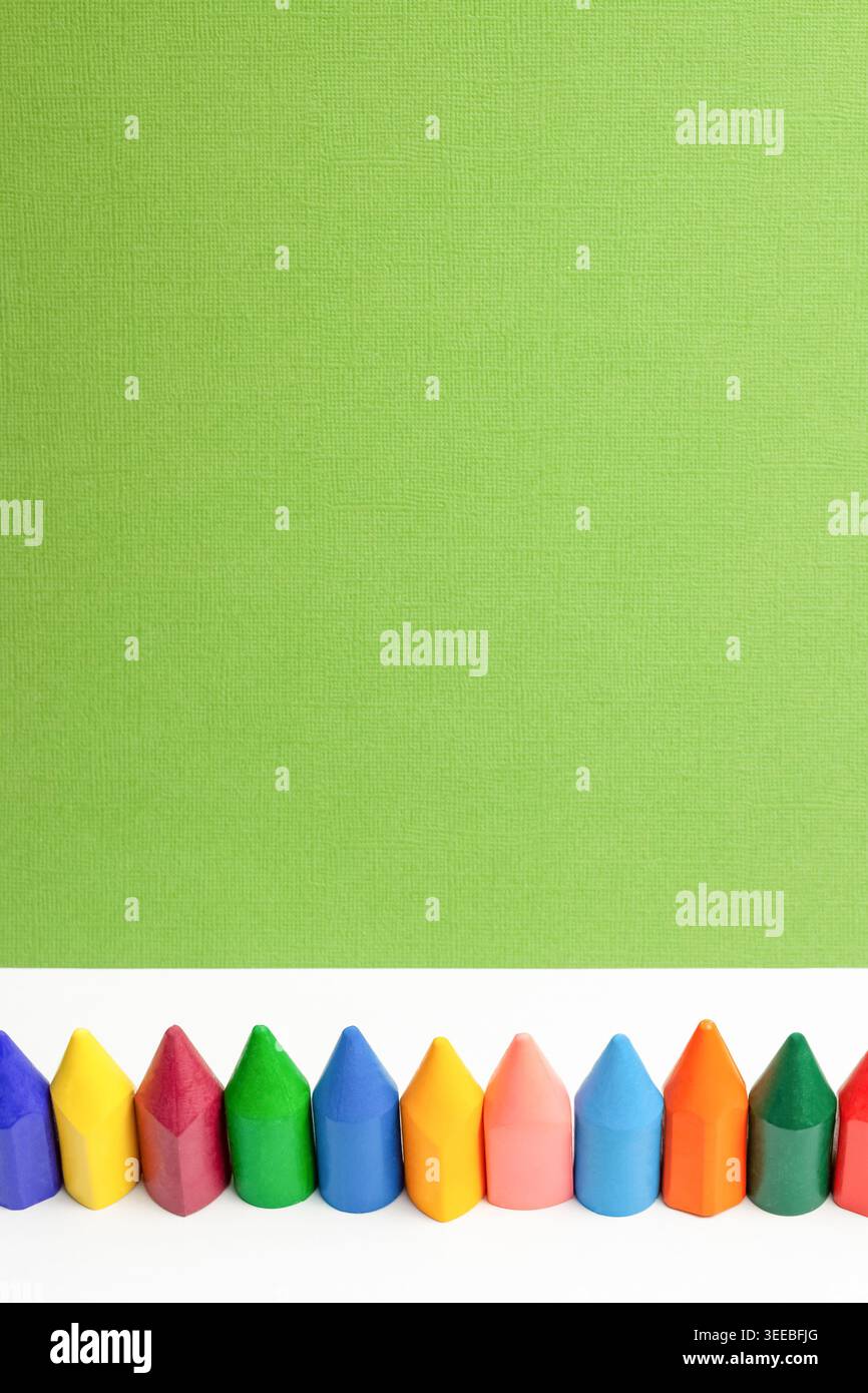 Matite macro multicolore luminose per bambini, sfondo bianco e verde isolato verticale Foto Stock
