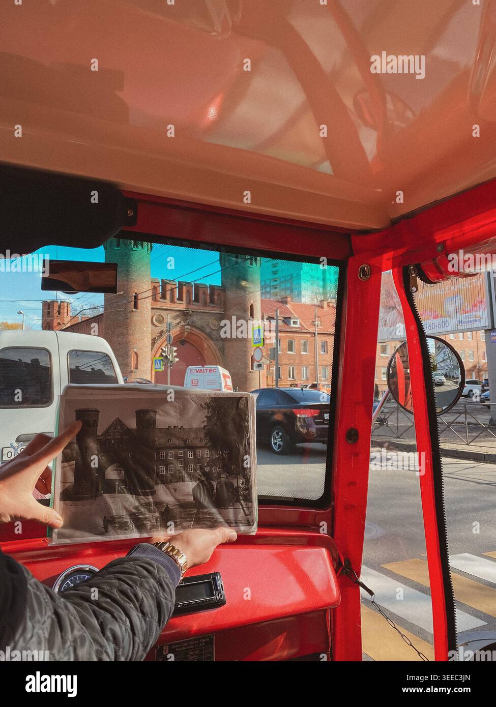 Kaliningrad, Russia - ottobre 25 2021: Vista dall'interno di un veicolo d'epoca con le mani in mano una vecchia fotografia che corrisponde a una porta storica della città all'esterno - Immagine stock catturata con smartphone