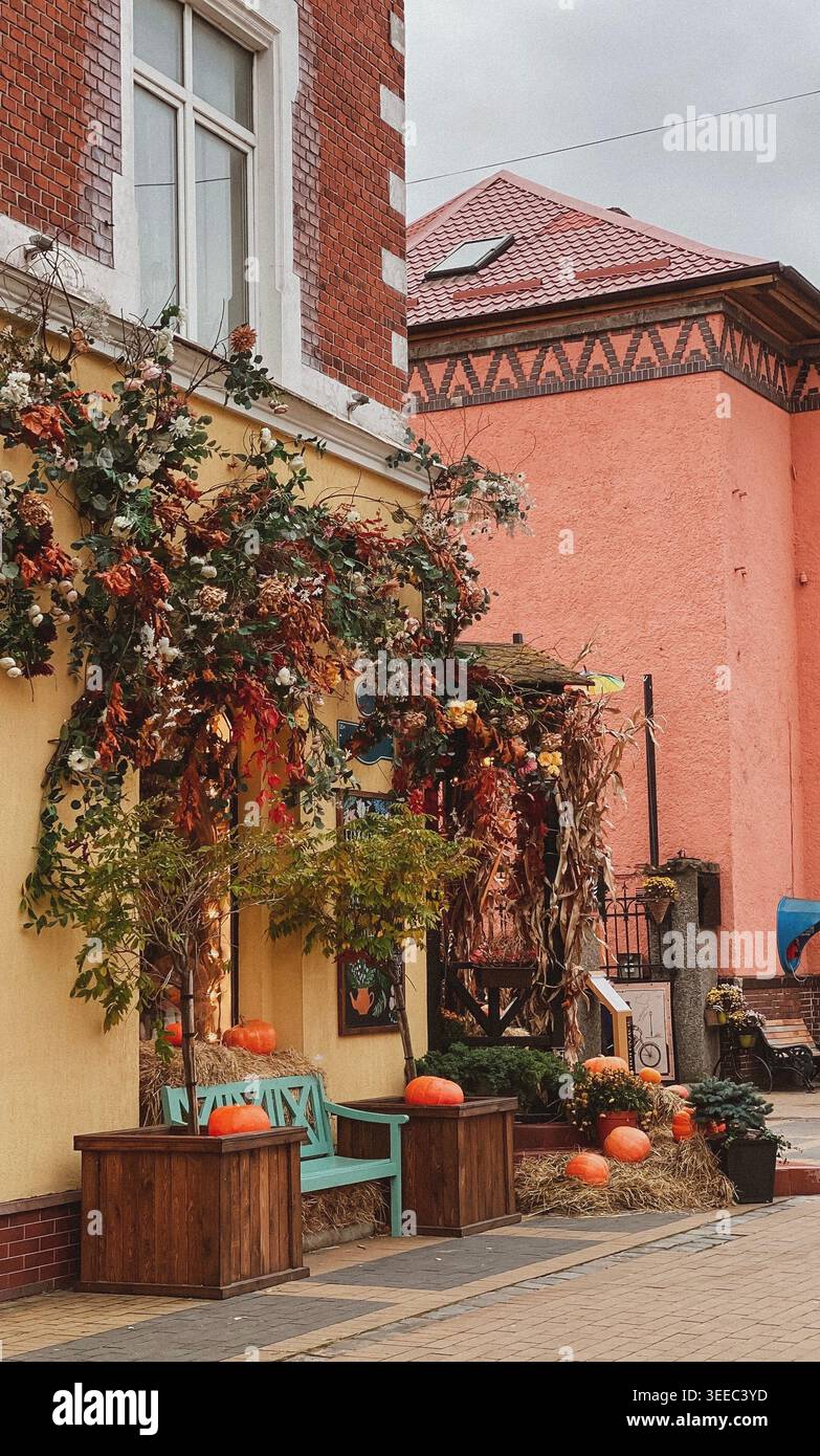 Intima scena di strada autunnale con facciata da caffè decorata, zucche, fieno e allestimento autunnale stagionale - Immagine stock catturata con smartphone