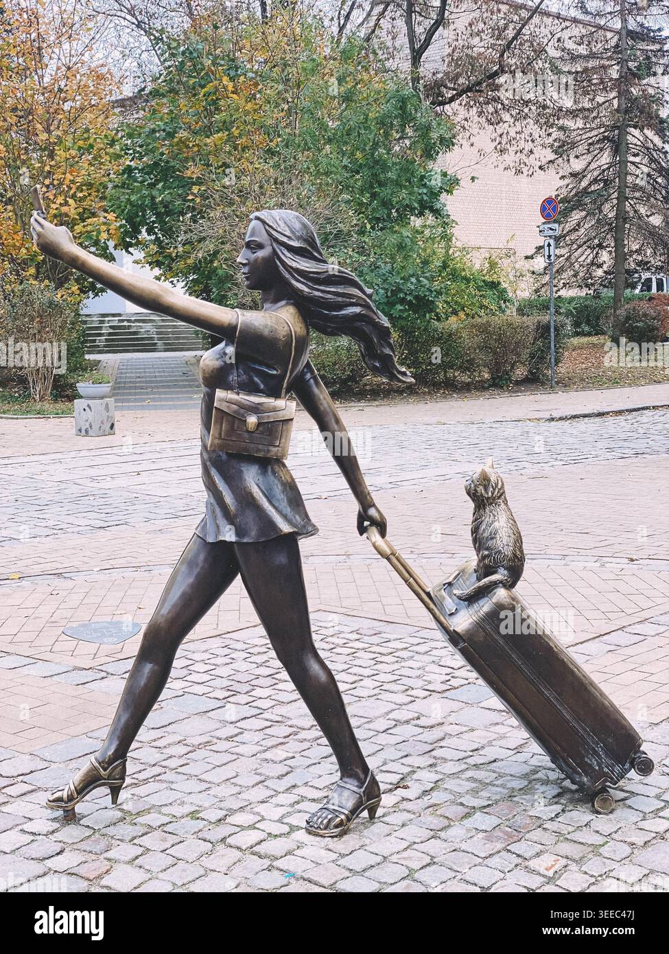 Zelenogradsk, Russia - ottobre 26 2021: Scultura in bronzo di una donna elegante che scatta un selfie mentre cammina con valigia e gatto nella città europea di bronz Foto Stock
