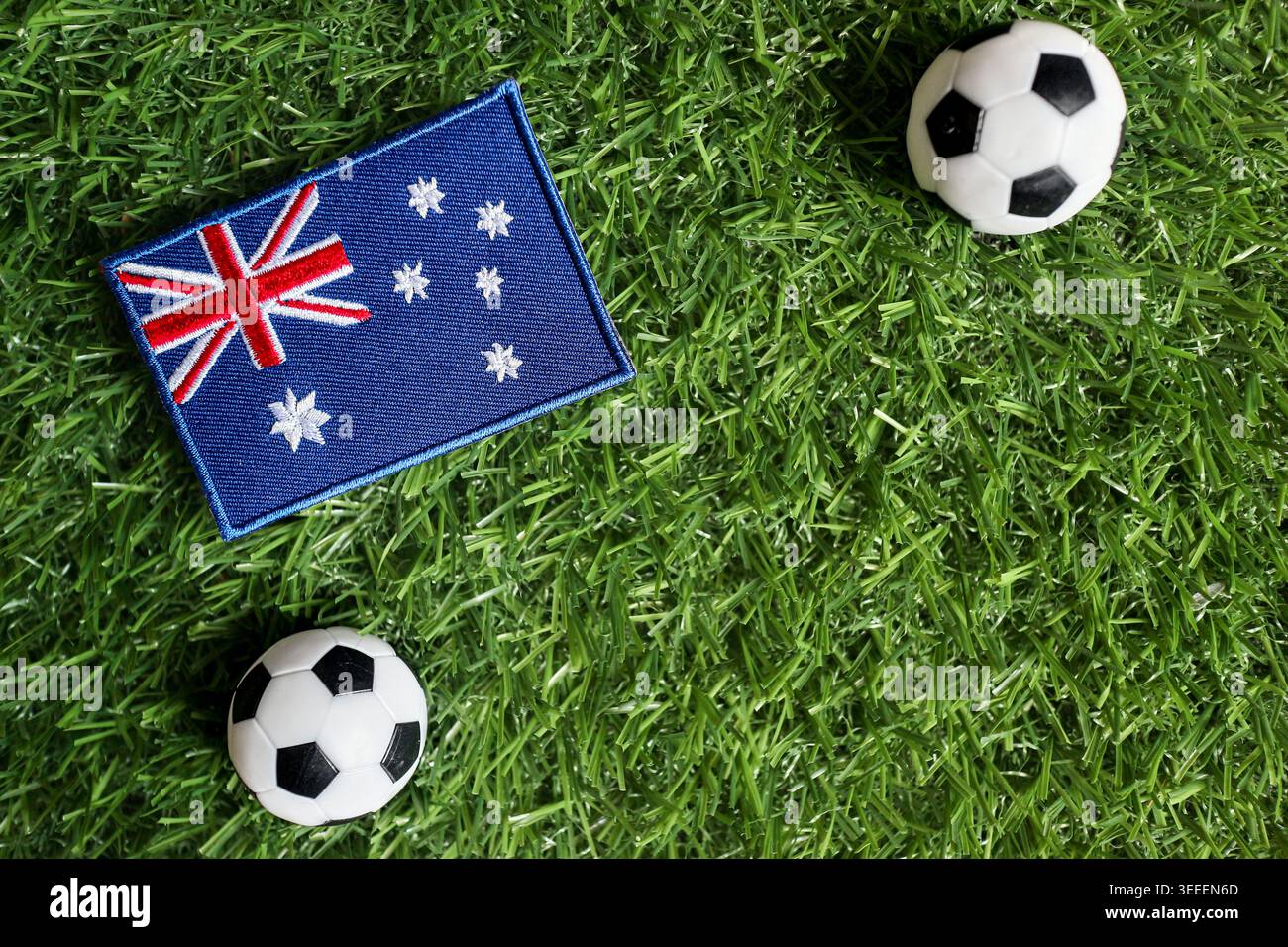 Concetto di tifoso australiano con bandiera nazionale e palloni da calcio su erba verde che simboleggiano la competizione globale e il lavoro di squadra. Foto Stock