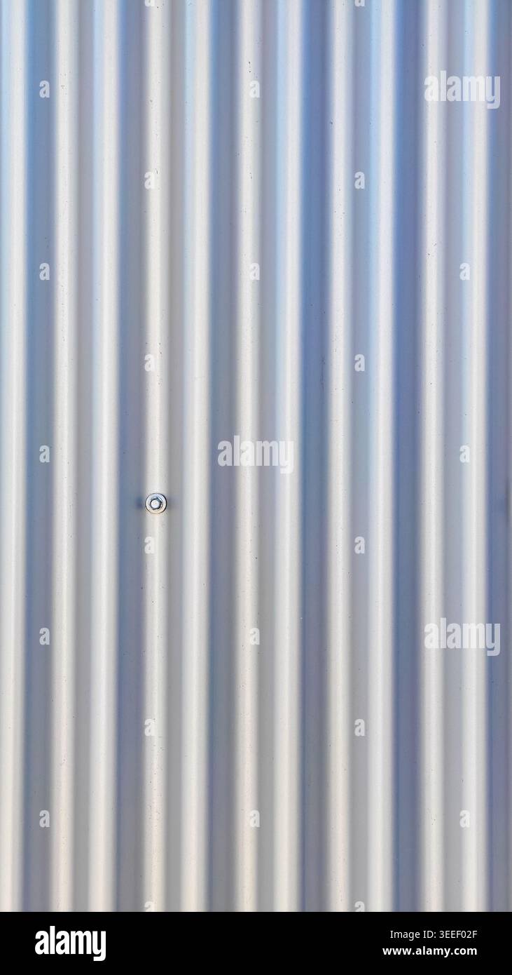 Facciata in lamiera, ondulata nella struttura. Struttura scanalata con una vite al centro. Gradienti neutri leggeri ed estetica industriale. Ottimo per ba Foto Stock