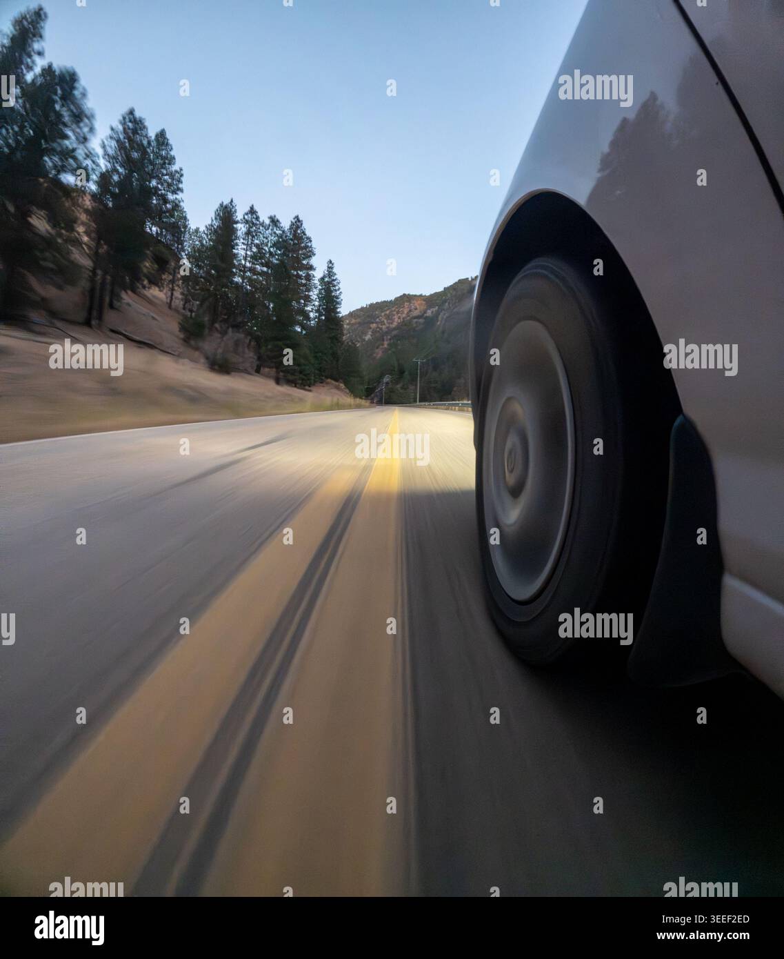 La ruota dell'auto gira velocemente su una strada sfocata Foto Stock