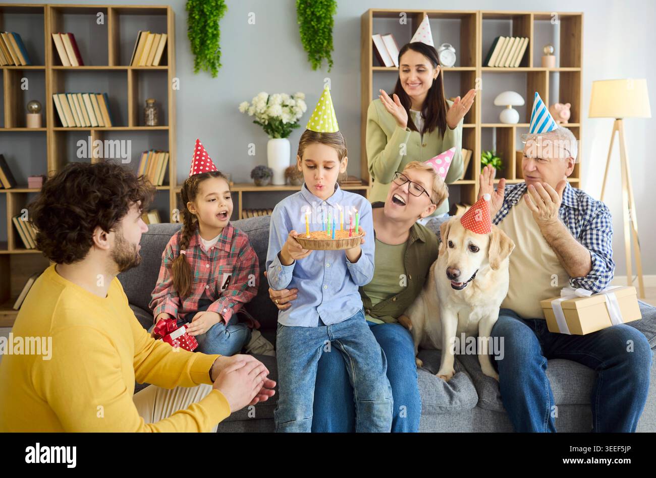 Buona festa di compleanno multigenerazionale in famiglia a casa con torta, candele e cane Foto Stock