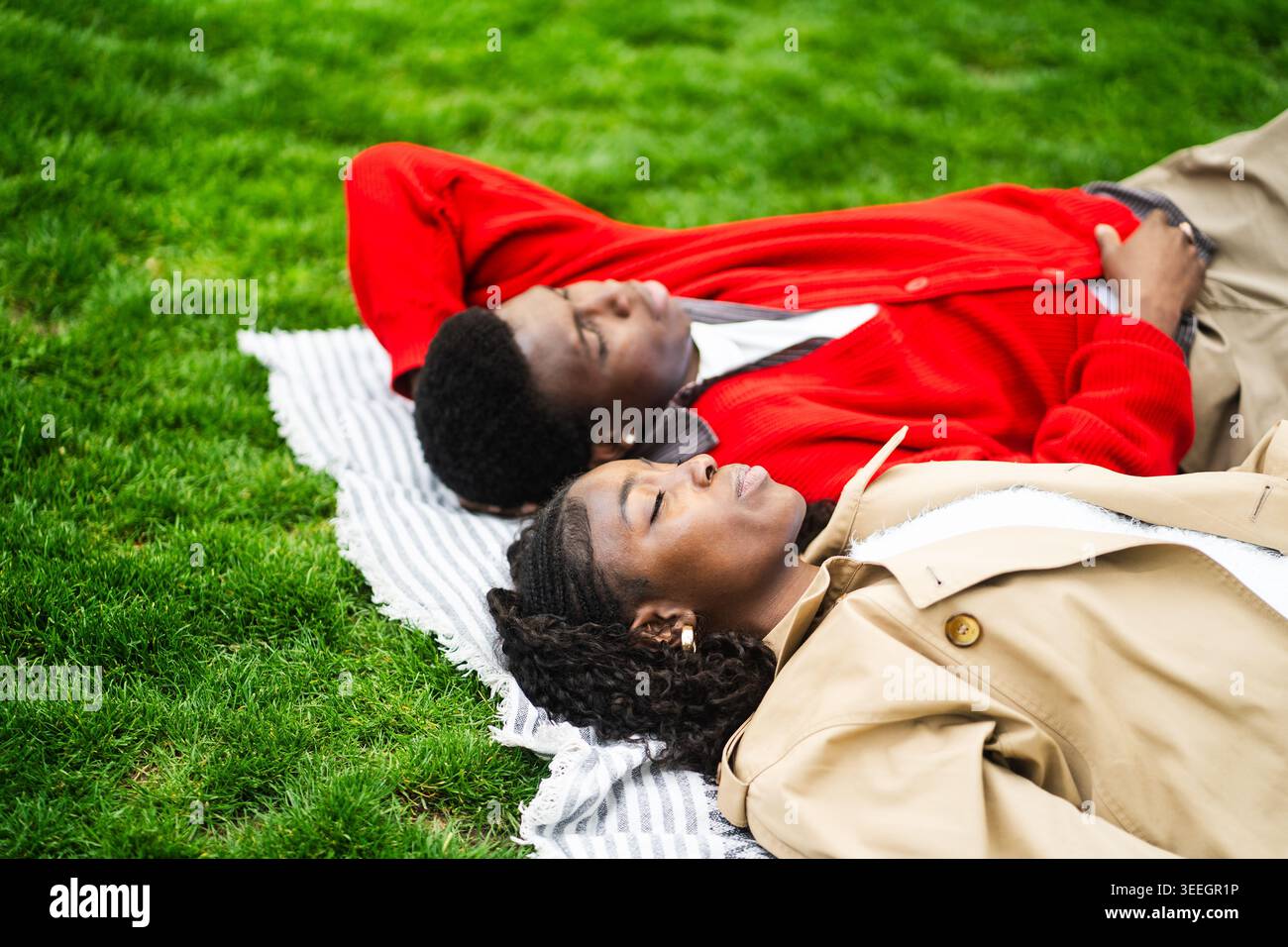Coppie afroamericane che si rilassano sull'erba nel parco godendosi momenti tranquilli lontano dalla città rumorosa. Foto Stock