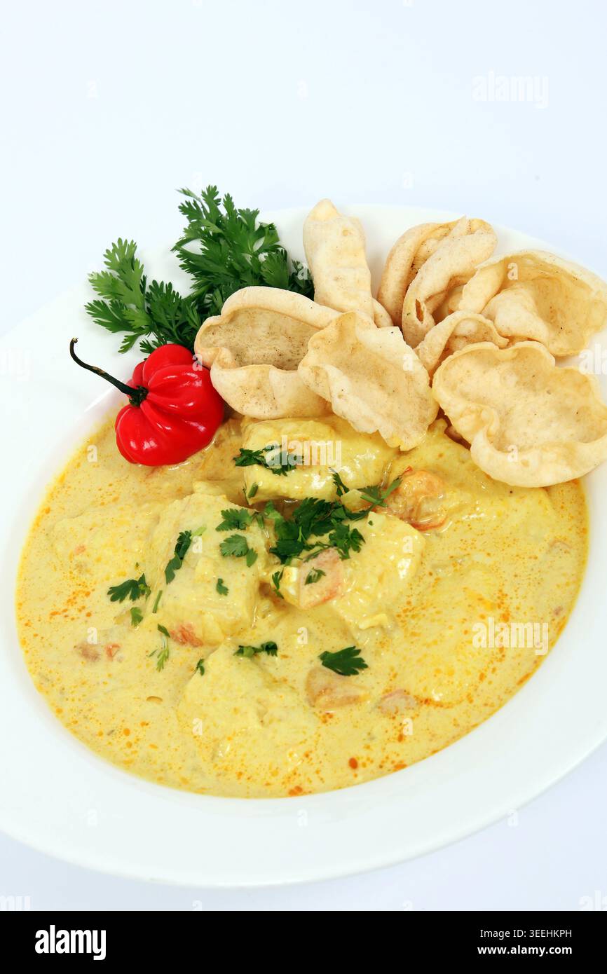 Un curry di pesce di Goan servito con peperoncino rosso, coriandolo e mini papadum. Foto Stock