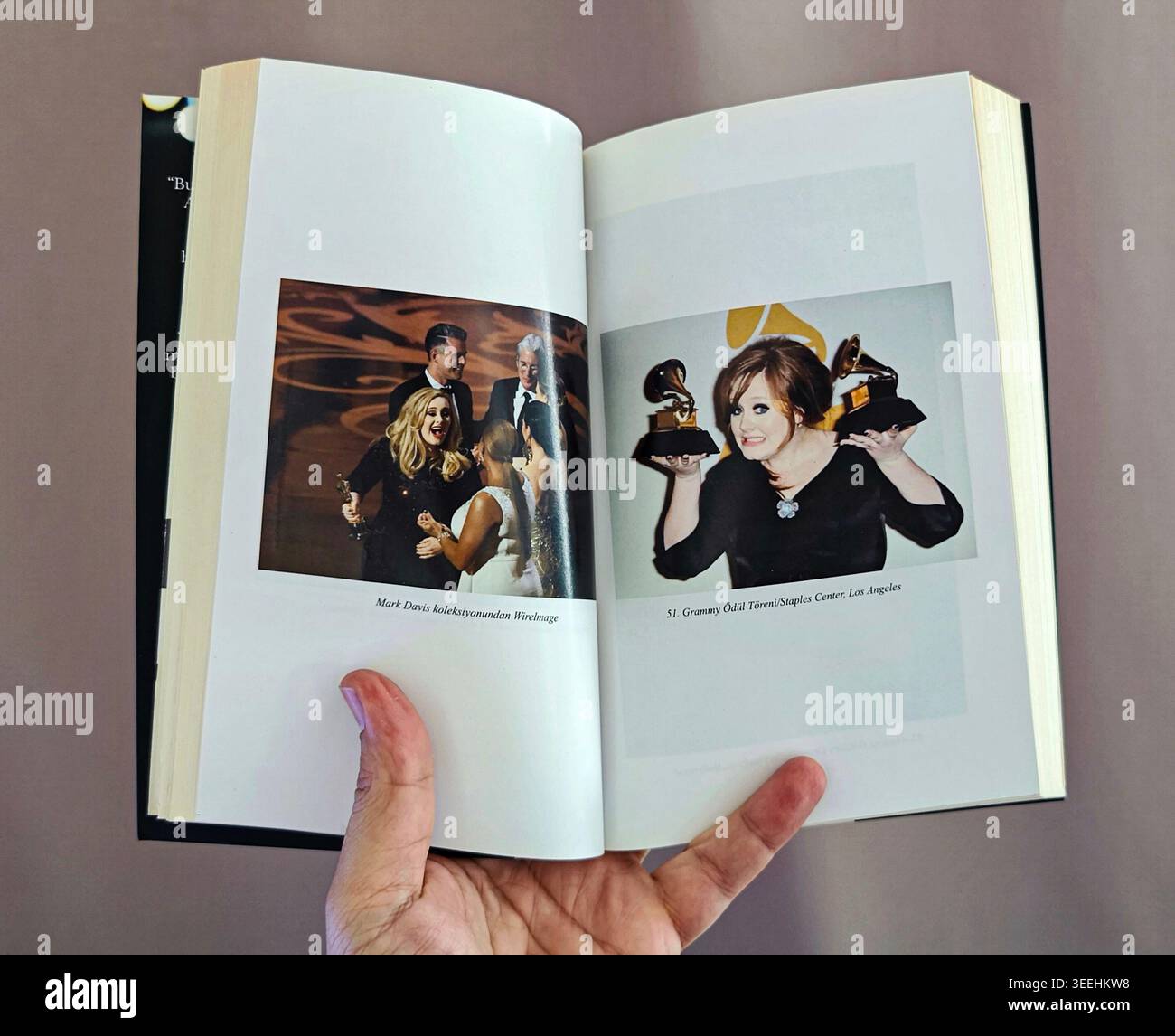Pagine aperte del libro biografico di Adele che mostra le foto stampate a colori del cantante durante le cerimonie di premiazione della musica, tenendo a mano il libro cartaceo. Foto Stock