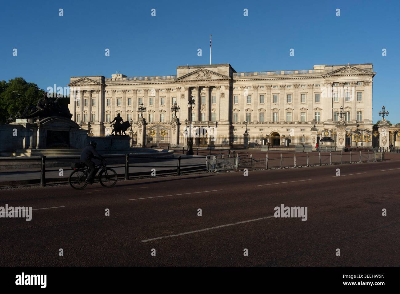 Un ciclista attraversa Buckingham Palace, Londra, in una mattinata tranquilla. Foto Stock