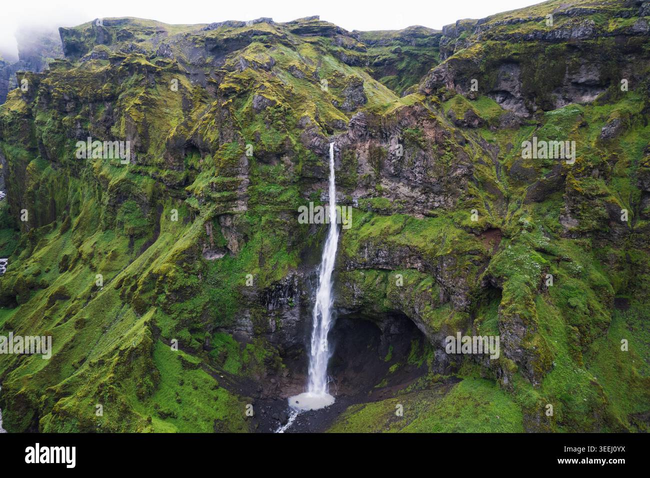 Vista aerea del Mulagljufur Canyon con un'alta cascata che scende da ripide scogliere verdi nella regione orientale dell'Islanda. Foto Stock
