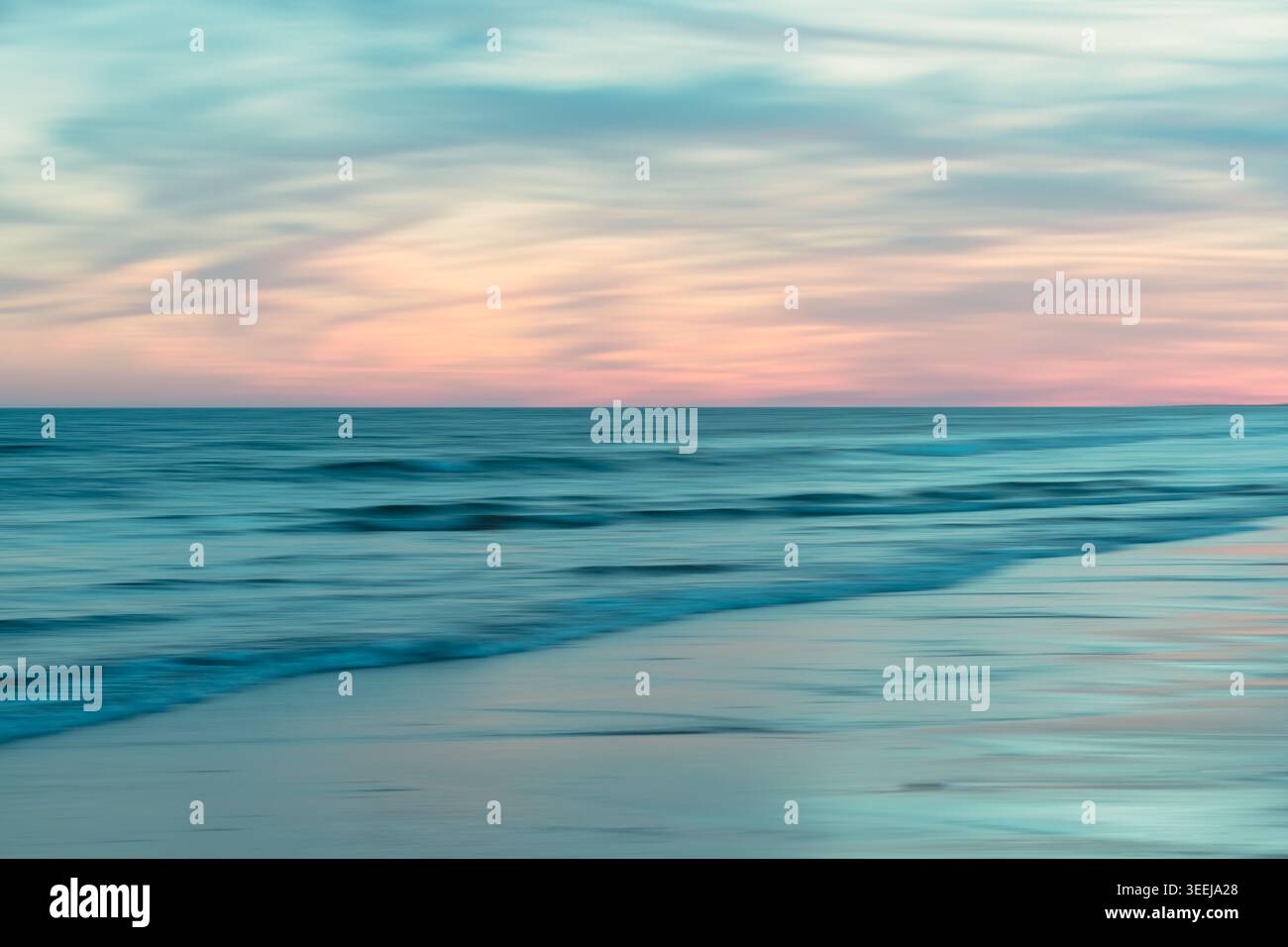 La lunga esposizione ammorbidisce il movimento delle onde oceaniche e dipinge il cielo in colori pastello al crepuscolo. Foto Stock