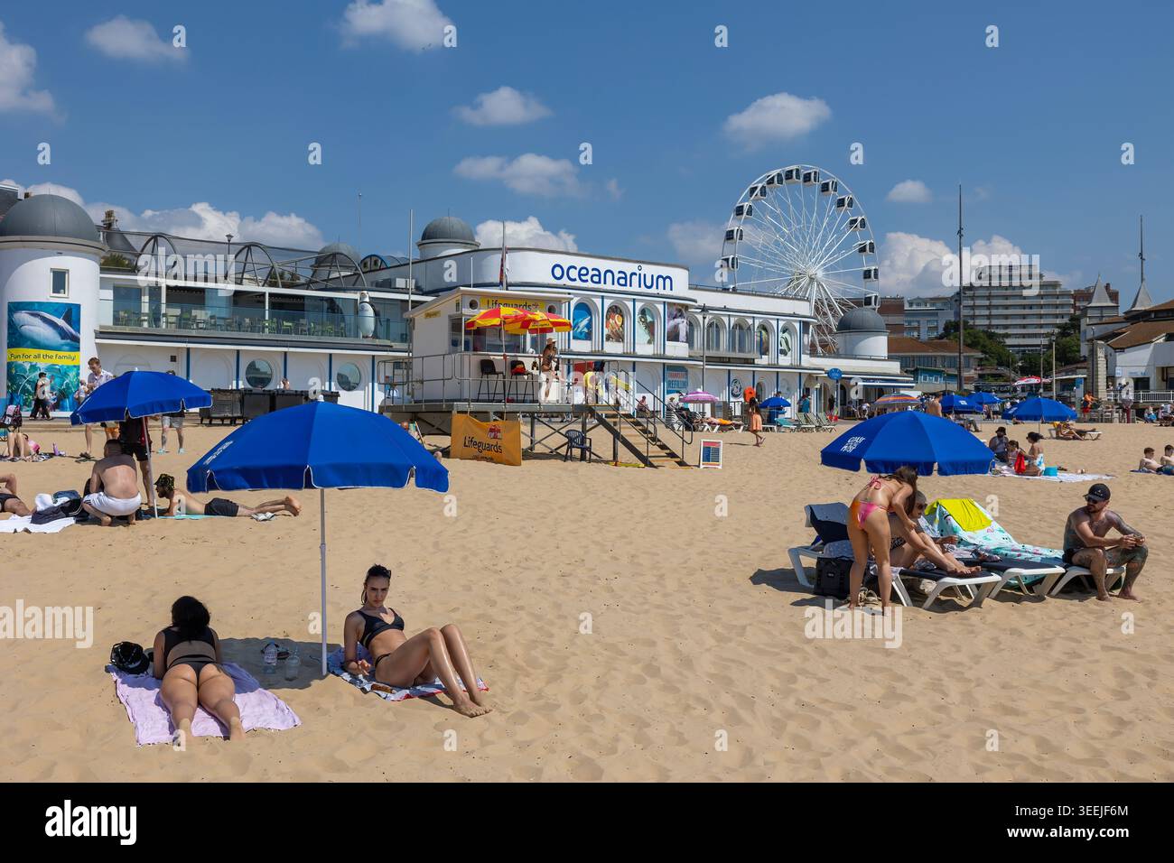 Spiaggia di Bournemouth con vista sull'Oceanarium e sulla ruota panoramica: I bagnanti si godono una calda giornata estiva nel Dorset, in Inghilterra. Foto Stock