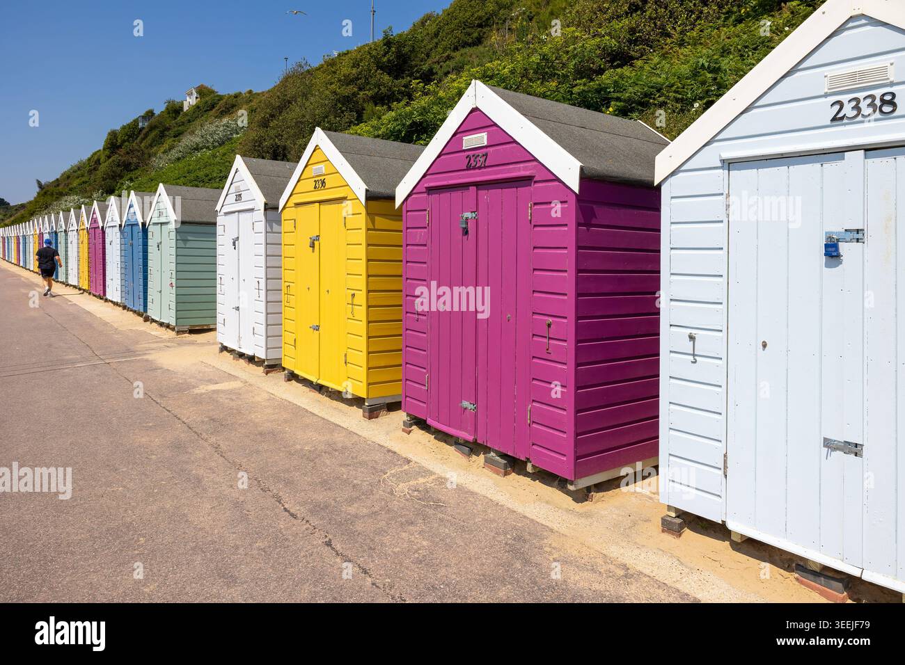 Colorate capanne sulla spiaggia lungo il lungomare di Bournemouth, Dorset, Inghilterra, con una vivace architettura marina sotto i cieli estivi. Foto Stock