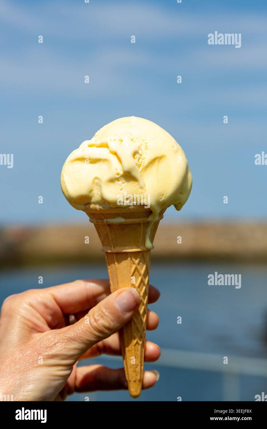 Primo piano di un gelato alla vaniglia che si scioglie in un tradizionale cono di waffle Foto Stock