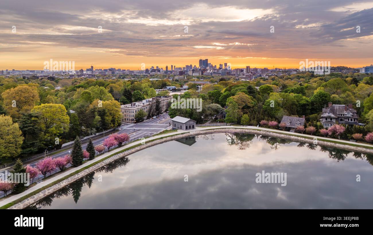 Vista aerea del lago artificiale Brookline, circondato da fiori di ciliegio e vegetazione lussureggiante, con lo skyline di Boston all'alba a Brookline, Massachusetts Foto Stock
