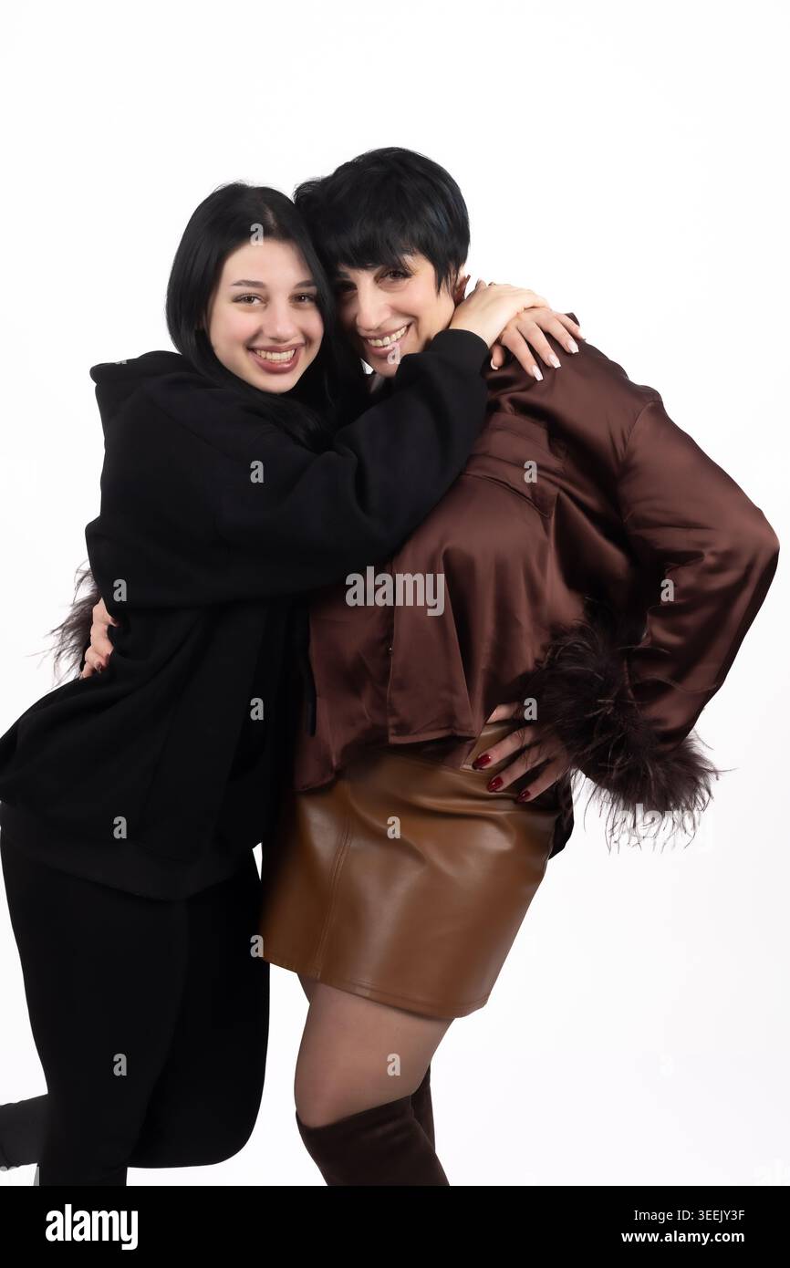 Due donne con cappotti invernali che si abbracciano e sorridono per fotogra professionale... Foto Stock