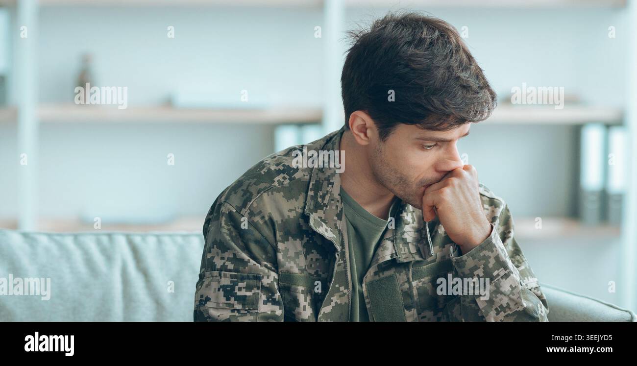 Uomo militare seduto sul divano pensando alle sue esperienze e ai suoi piani futuri durante il tempo tranquillo Foto Stock