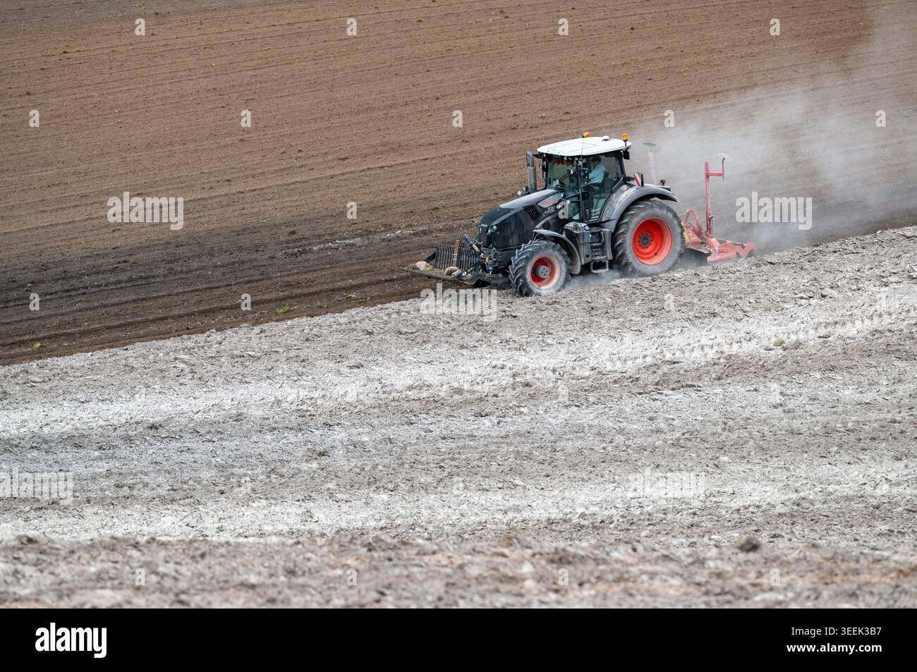 Claas Axion 830 eruttante di potenza in calce appena sparsa su un campo arato. Il calcare in polvere aiuta la fertilità del terreno. Cumbria, Regno Unito. Foto Stock