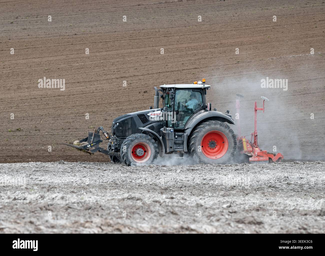 Claas Axion 830 eruttante di potenza in calce appena sparsa su un campo arato. Il calcare in polvere aiuta la fertilità del terreno. Cumbria, Regno Unito. Foto Stock