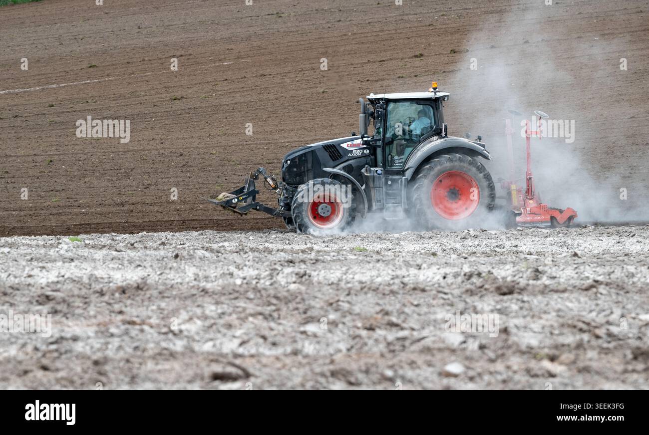 Claas Axion 830 eruttante di potenza in calce appena sparsa su un campo arato. Il calcare in polvere aiuta la fertilità del terreno. Cumbria, Regno Unito. Foto Stock