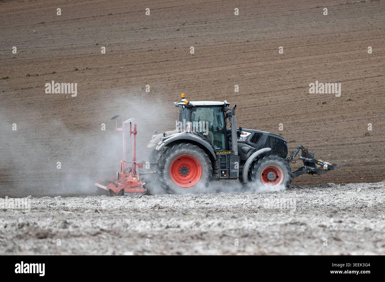 Claas Axion 830 eruttante di potenza in calce appena sparsa su un campo arato. Il calcare in polvere aiuta la fertilità del terreno. Cumbria, Regno Unito. Foto Stock