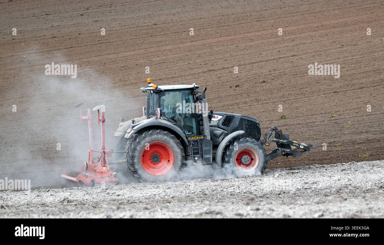 Claas Axion 830 eruttante di potenza in calce appena sparsa su un campo arato. Il calcare in polvere aiuta la fertilità del terreno. Cumbria, Regno Unito. Foto Stock