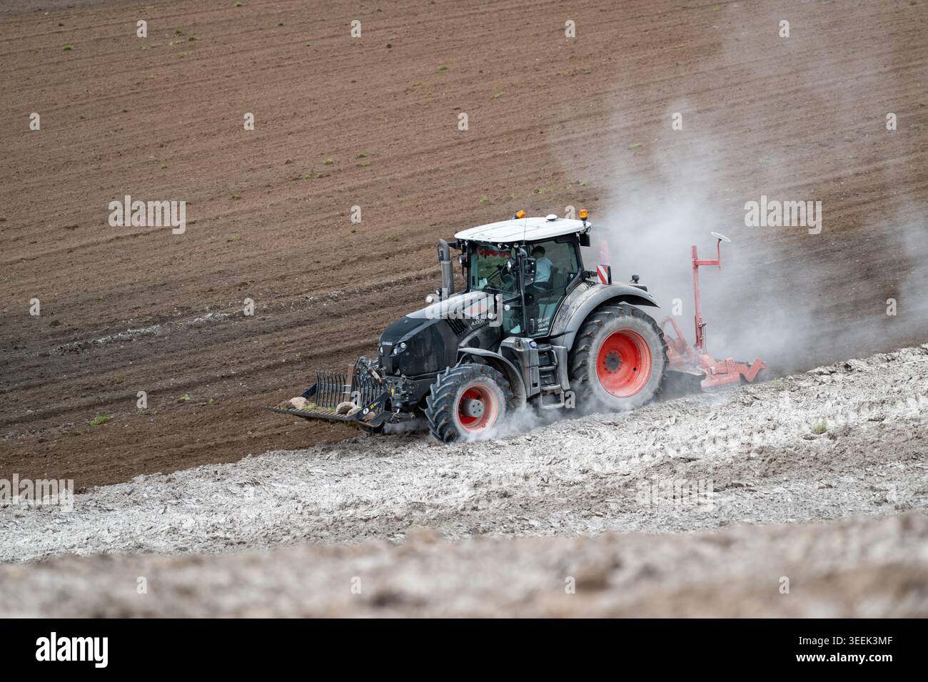 Claas Axion 830 eruttante di potenza in calce appena sparsa su un campo arato. Il calcare in polvere aiuta la fertilità del terreno. Cumbria, Regno Unito. Foto Stock