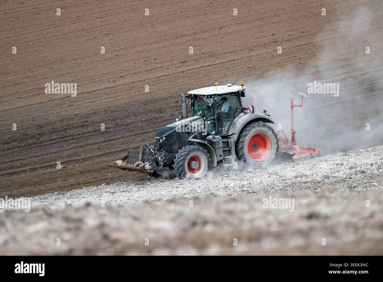 Claas Axion 830 eruttante di potenza in calce appena sparsa su un campo arato. Il calcare in polvere aiuta la fertilità del terreno. Cumbria, Regno Unito. Foto Stock