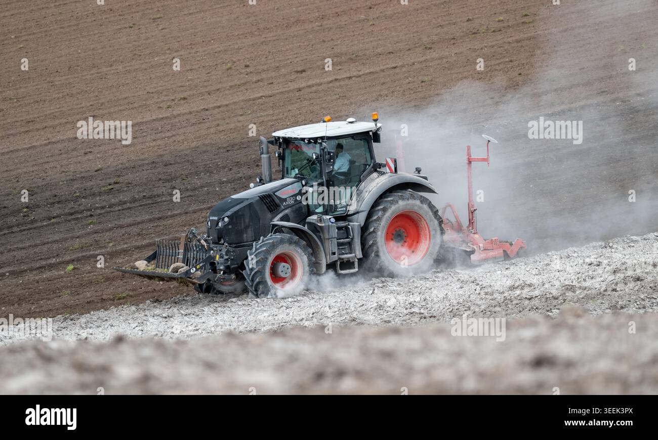 Claas Axion 830 eruttante di potenza in calce appena sparsa su un campo arato. Il calcare in polvere aiuta la fertilità del terreno. Cumbria, Regno Unito. Foto Stock