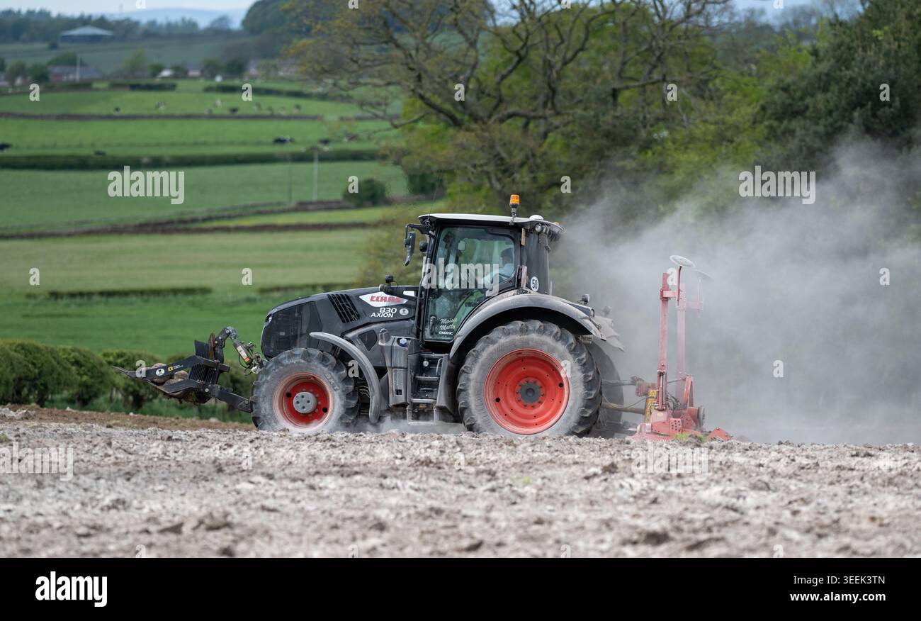 Claas Axion 830 eruttante di potenza in calce appena sparsa su un campo arato. Il calcare in polvere aiuta la fertilità del terreno. Cumbria, Regno Unito. Foto Stock