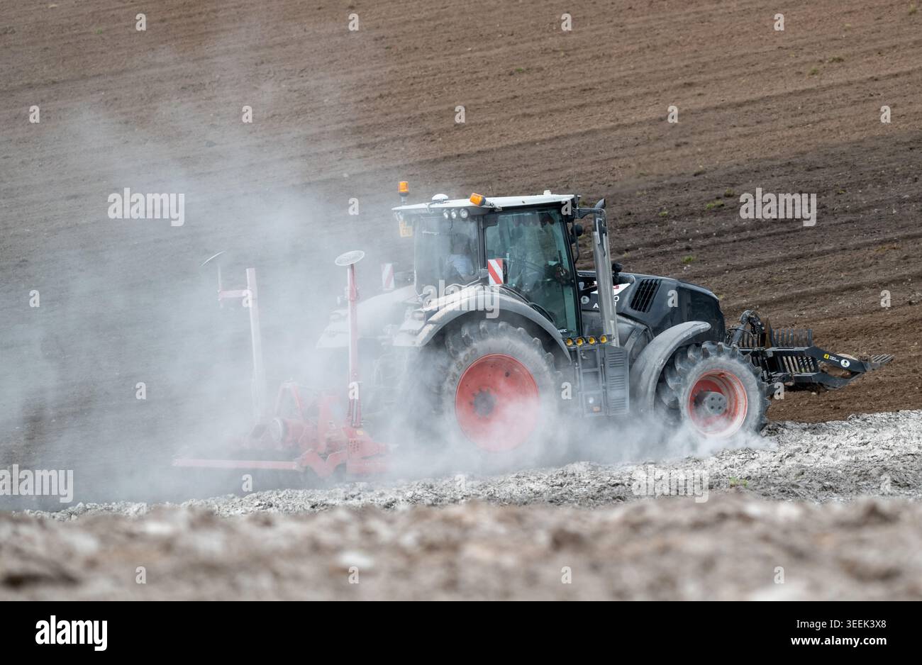 Claas Axion 830 eruttante di potenza in calce appena sparsa su un campo arato. Il calcare in polvere aiuta la fertilità del terreno. Cumbria, Regno Unito. Foto Stock