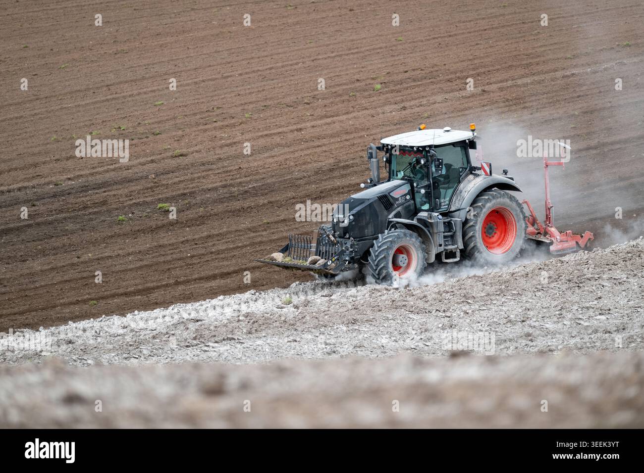 Claas Axion 830 eruttante di potenza in calce appena sparsa su un campo arato. Il calcare in polvere aiuta la fertilità del terreno. Cumbria, Regno Unito. Foto Stock