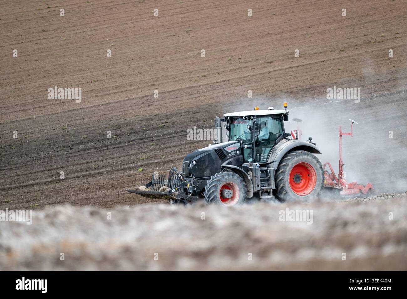 Claas Axion 830 eruttante di potenza in calce appena sparsa su un campo arato. Il calcare in polvere aiuta la fertilità del terreno. Cumbria, Regno Unito. Foto Stock