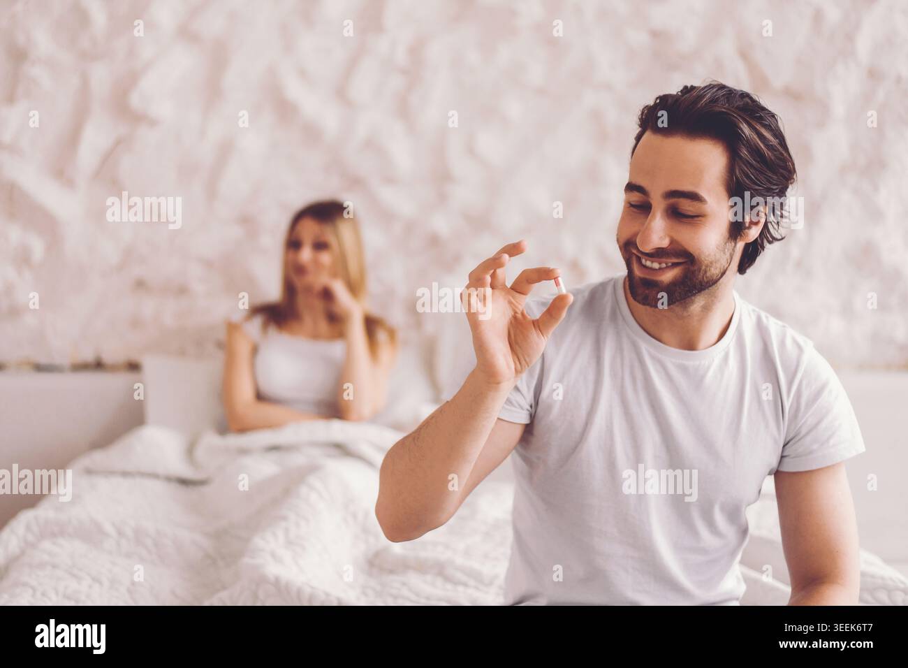 L'uomo mostra piccoli oggetti alla donna mentre è seduto su un letto in una stanza durante il giorno Foto Stock