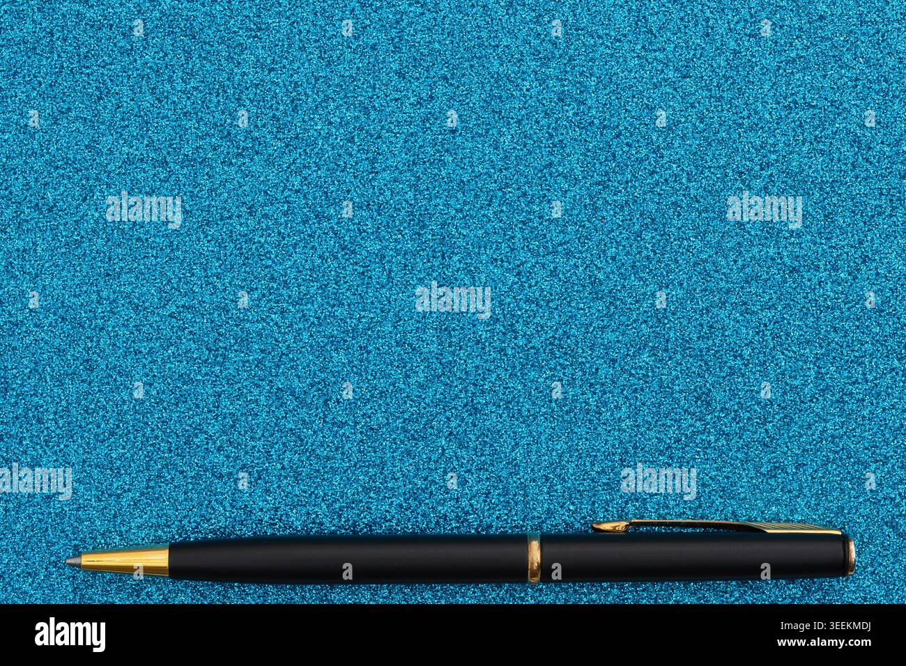 Elegante pennarello nero con finitura oro adagiato su una superficie scintillante blu, adatto per articoli di cancelleria e scritture di lusso. Foto Stock