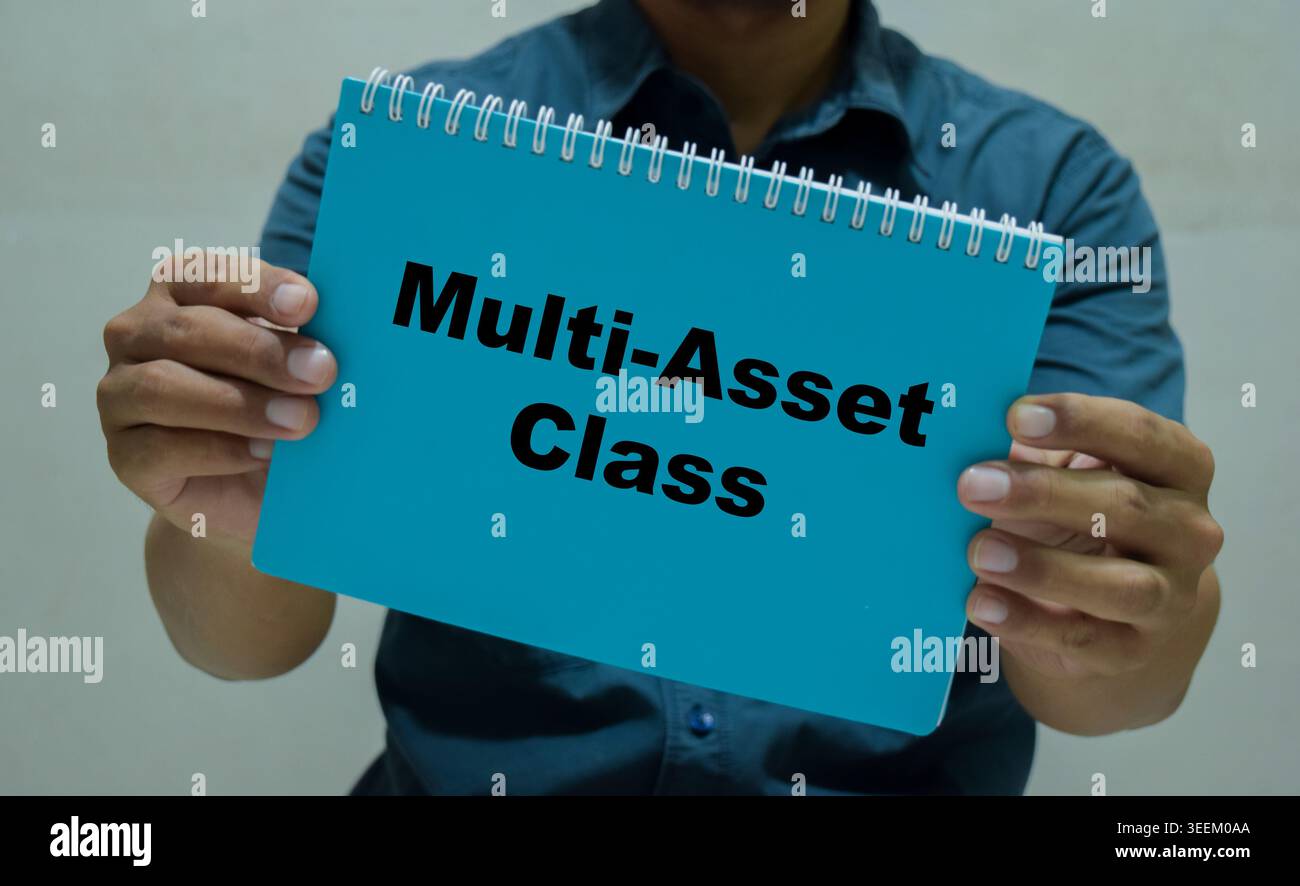 Un uomo d'affari ha in mano un libro con il nome della classe multi-asset. Foto Stock