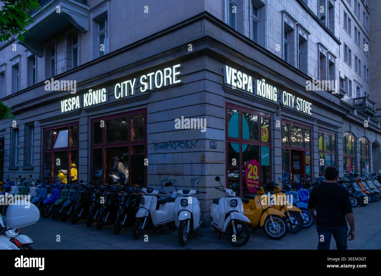 Vista serale del Vespa König City Store a Friedrichshain con file di scooter parcheggiati di fronte al negozio, Berlino, Germania. Foto Stock