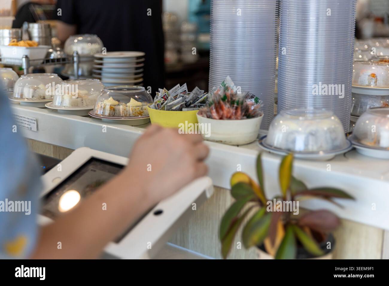 Un cliente che utilizza un tablet digitale per ordinare il cibo in un moderno ristorante giapponese di sushi train a Brisbane, Australia. (2025) Foto Stock