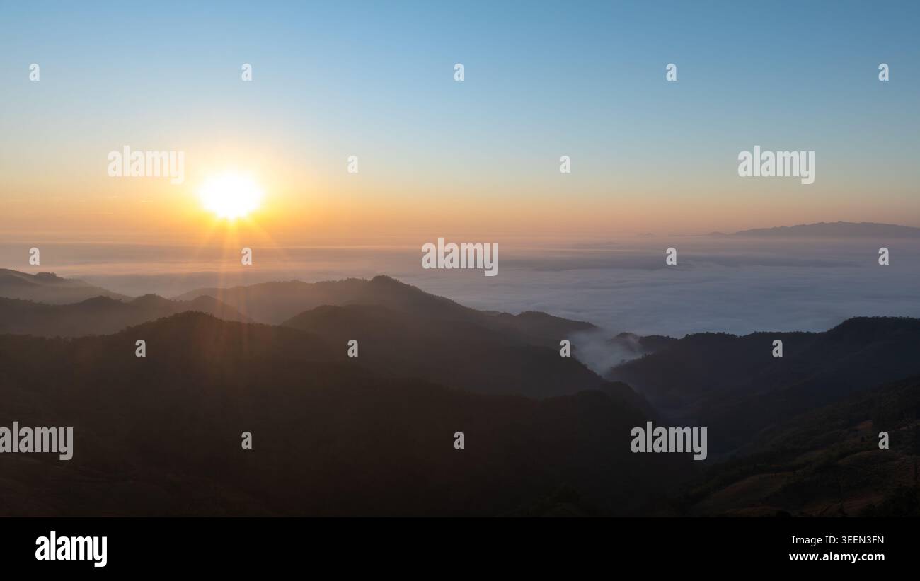 Una vista panoramica del paesaggio di profili di montagna stratificati che emergono da un mare di nebbia mattutina all'alba, perfetto per viaggi e temi naturalistici. Foto Stock
