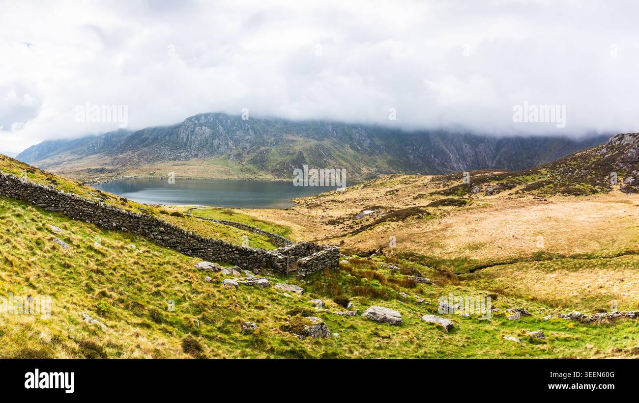 Un ampio panorama che si affaccia sulla spettacolare ciotola di Cwm Idwal nel Galles del Nord. In primo piano, un tradizionale muro di pietra a secco gallese e un piccolo rettangu Foto Stock