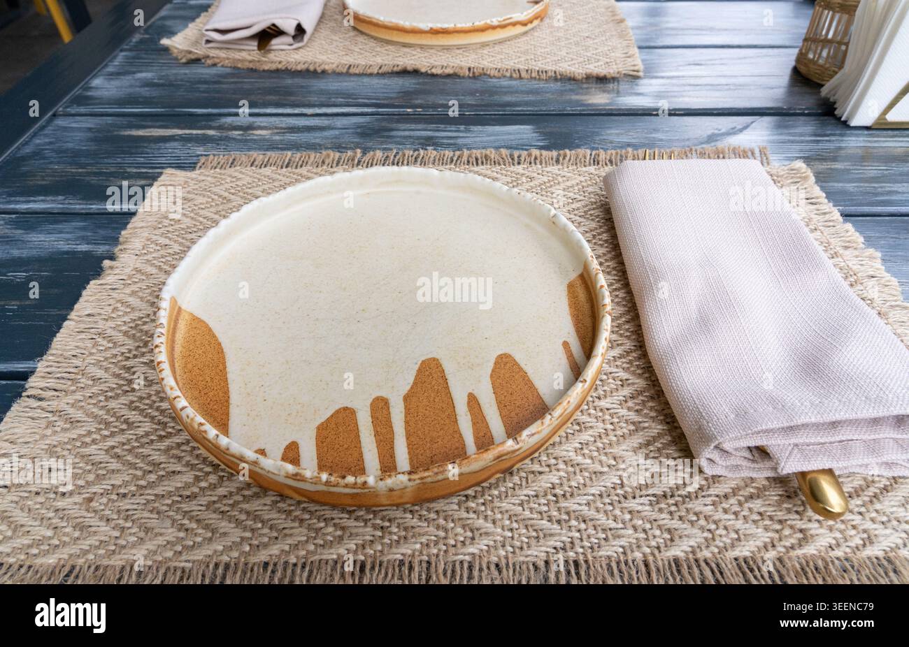 Mockup piatto vuoto del ristorante, tavolo rustico in legno scuro con un piatto bianco, un tovagliolo beige e un tovagliolo in burlap, cena in stile fattoria Foto Stock