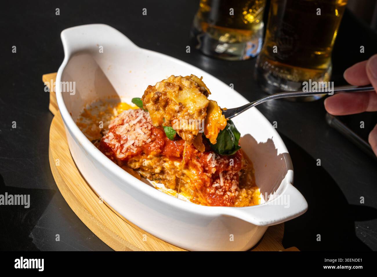 Lasagne, lasagne al forno, strati di pasta con formaggio, carne macinata, pomodoro. Lasagne sul tavolo del ristorante in strada in un giorno d'estate soleggiato, sfocate Foto Stock