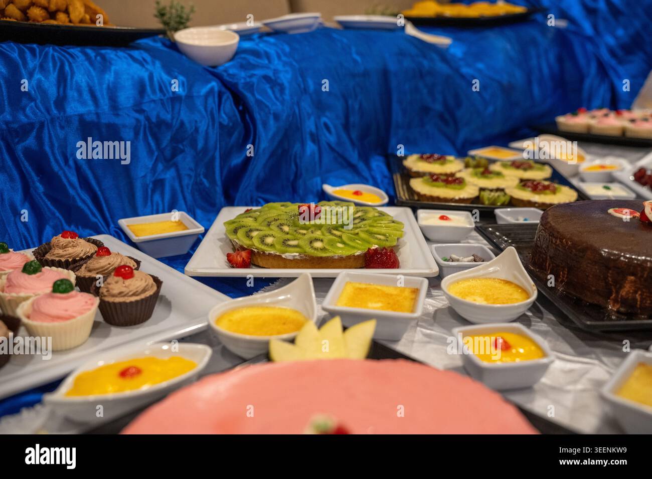Buffet di dessert con crostata kiwi, torta al cioccolato, cupcake e budini individuali per una selezione di dolci Foto Stock