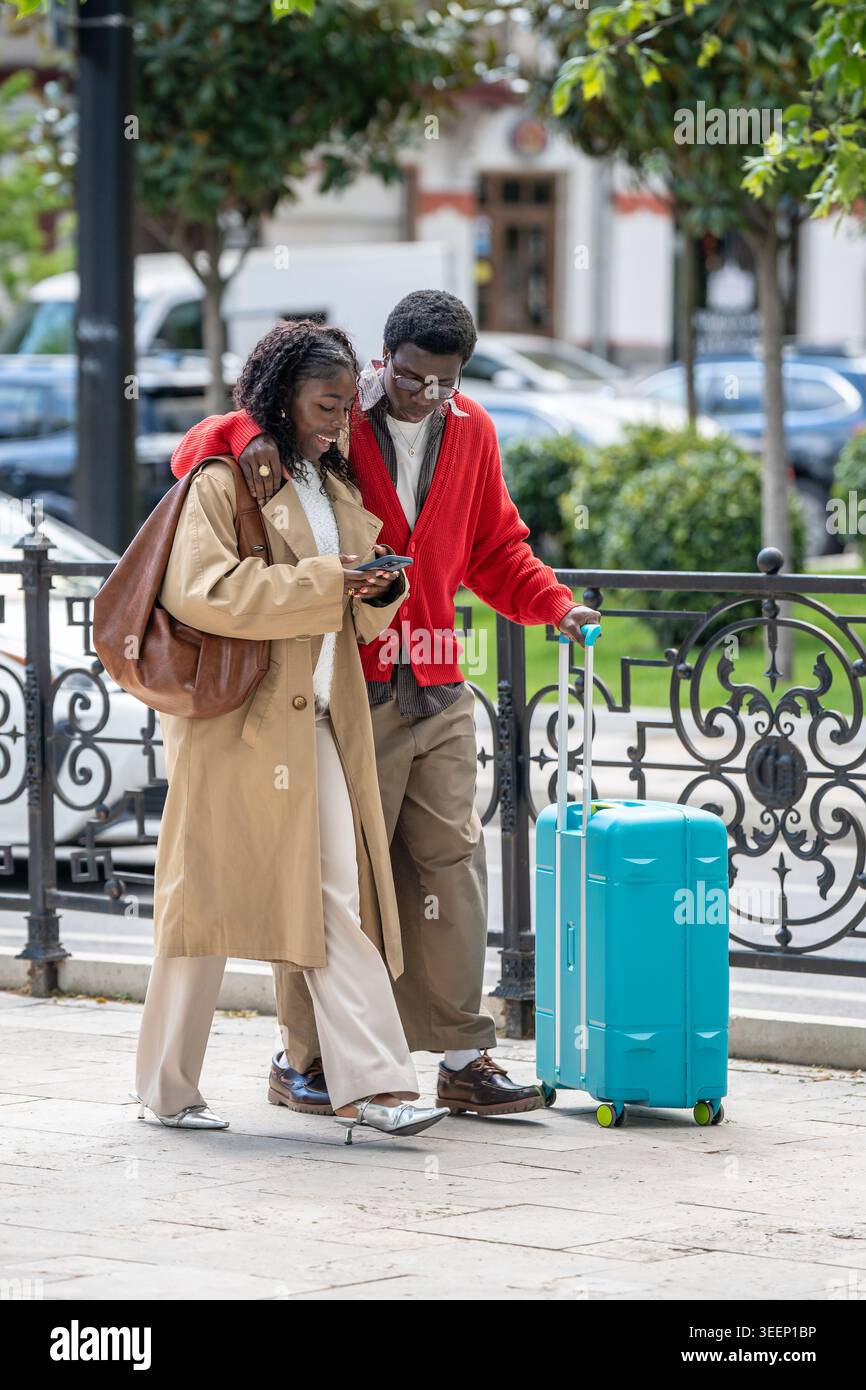 Sorridenti viaggiatori di coppia afroamericani sposati uomo e donna che camminano lungo la strada in nuova città. Foto Stock