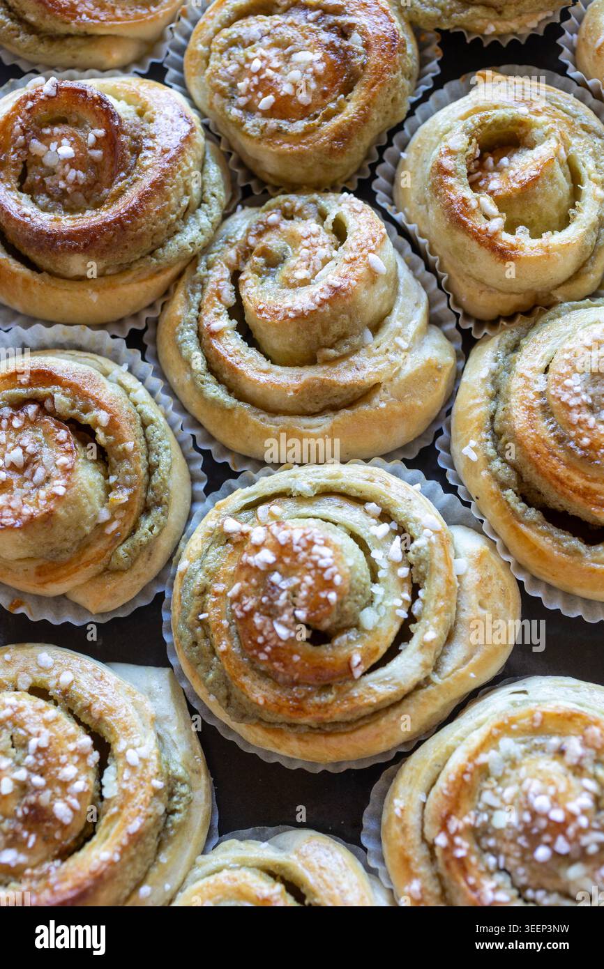 I panini al pistacchio dorati con le punte lucide e le perle di zucchero si trovano a stretto contatto con una luce calda e soffusa. Foto Stock