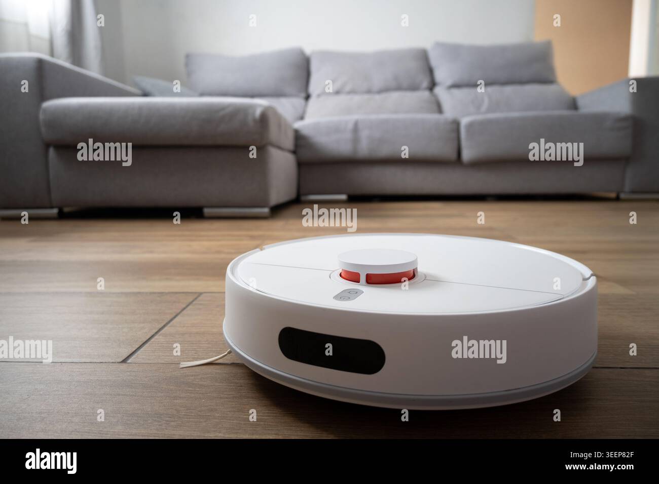 Aspirapolvere robot che pulisce il pavimento in legno nel soggiorno moderno Foto Stock