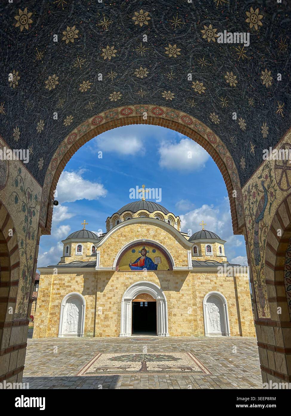 Monastero ortodosso a Kac, Serbia, incorniciato da un arco a mosaico ornato sotto un drammatico cielo blu. - Immagine stock catturata con smartphone