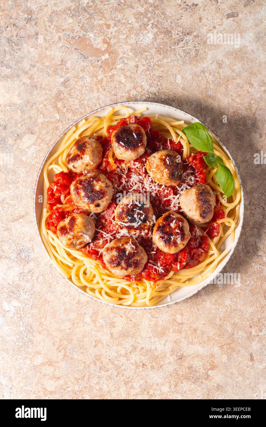 Un piatto di spaghetti classici conditi con polpette dorate e ricca salsa di pomodoro su un piatto di ceramica leggera. Foto Stock
