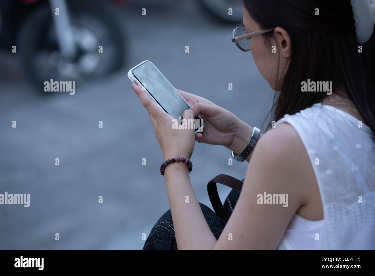 Donna seduta e che utilizza lo smartphone, momento personale con il telefono, utente mobile solitario, primo piano Foto Stock