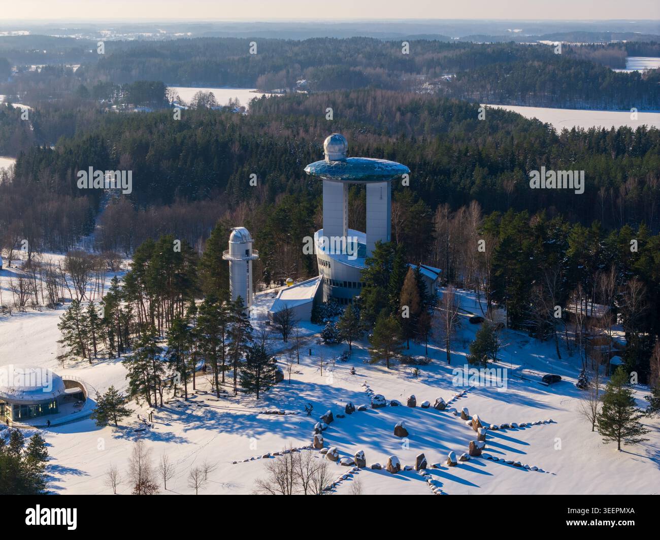Vista aerea del Museo lituano di Etnocosmologia con la sua torre futuristica, le cupole e un cerchio di pietre in una foresta innevata a Kulionys, Utenos apskr Foto Stock